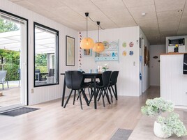 Un comedor moderno con una mesa de madera, sillas negras y una lámpara colgante naranja.
