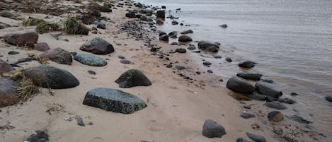 Una platja rocosa amb grans roques i vegetació dispersa.