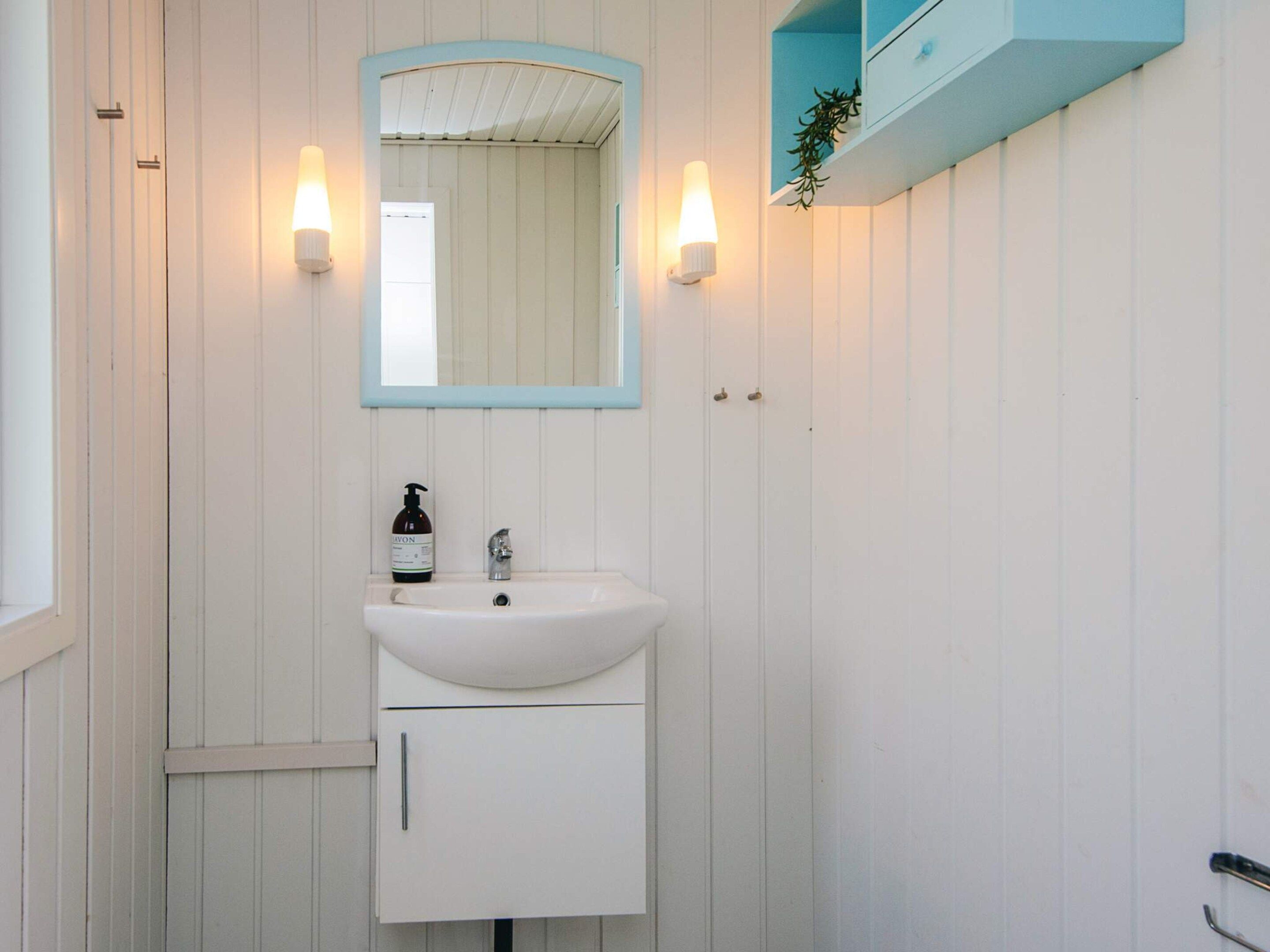 A bathroom with a white sink, a mirror, and two wall-mounted lights.