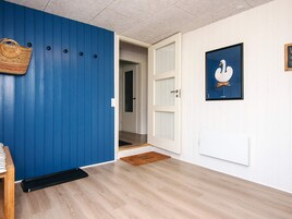Un pasillo con una pared azul, una puerta blanca, un cuadro de un cisne enmarcado y un bolso tejido en la pared.