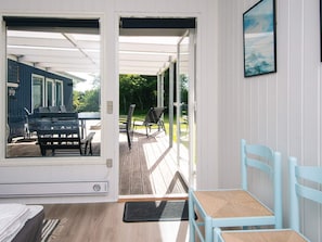 A room with a wooden floor, a bed, a window, and a door leading to an outdoor deck with a table and chairs. - 6 Person Holiday Home in Tarm (Tarm)