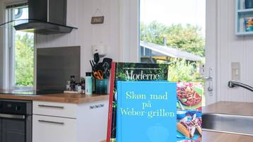 Uma cozinha com um livro intitulado 'Sken mad på Weber grillen' sobre o balcão.
