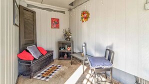 A cozy room with a sofa, a small table, and a chair. There is a decorative wreath on the wall and a shelf with various items.