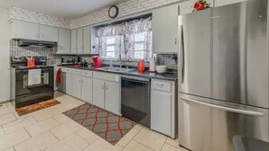 A modern kitchen with white cabinets, stainless steel appliances, and a red decorative item on the refrigerator.