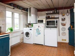 A compact kitchen with a washing machine, a microwave, and a small oven. - 6 Person Holiday Home in Augustenborg (Augustenborg)
