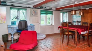 A room with a dining table, chairs, a red chair, a desk with a chair, a lamp, and a window with a view. - 6 Person Holiday Home in Augustenborg (Augustenborg)