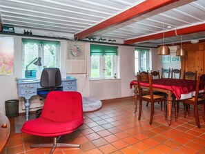 A room with a dining table, chairs, a red chair, a desk with a chair, a lamp, and a window with a view. - 6 Person Holiday Home in Augustenborg (Augustenborg)
