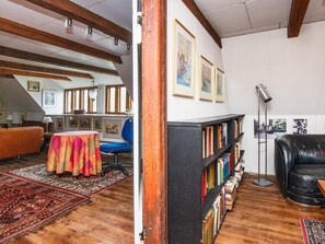 A room with a bookshelf, a leather chair, a table with a colorful tablecloth, and a patterned rug. - 6 Person Holiday Home in Augustenborg (Augustenborg)