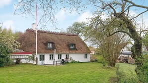 A white house with a thatched roof, a grassy yard, and a large tree. - 6 Person Holiday Home in Augustenborg (Augustenborg)
