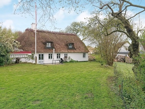 A white house with a thatched roof, a grassy yard, and a large tree. - 6 Person Holiday Home in Augustenborg (Augustenborg)