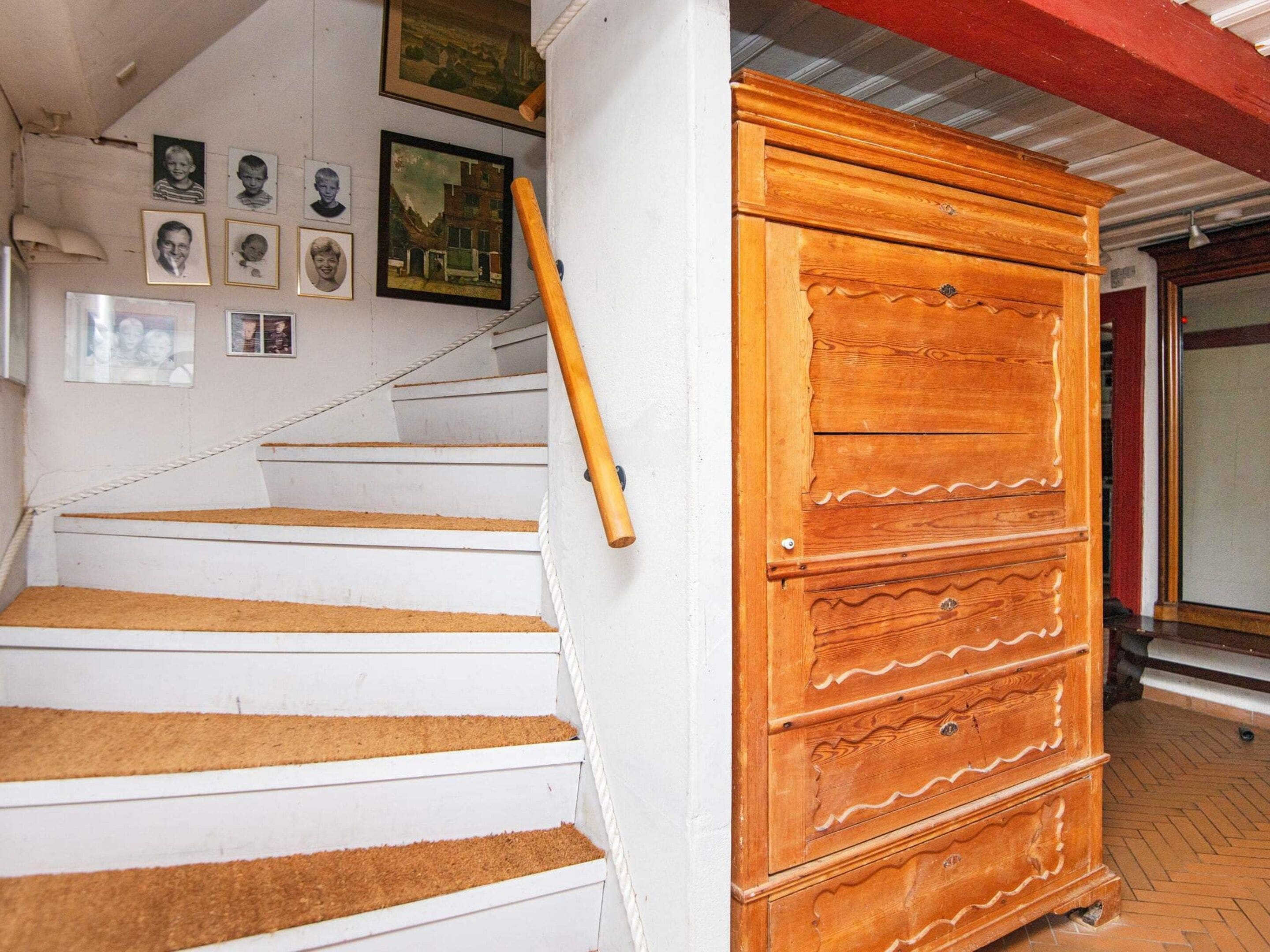 Una escalera con un armario de madera a la derecha.