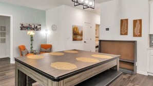 Un espace repas moderne avec une grande table rectangulaire, des bancs et un téléviseur fixé au mur.