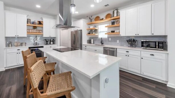 Une cuisine moderne avec des meubles blancs, un îlot central doté de sièges et des appareils électroménagers intégrés.