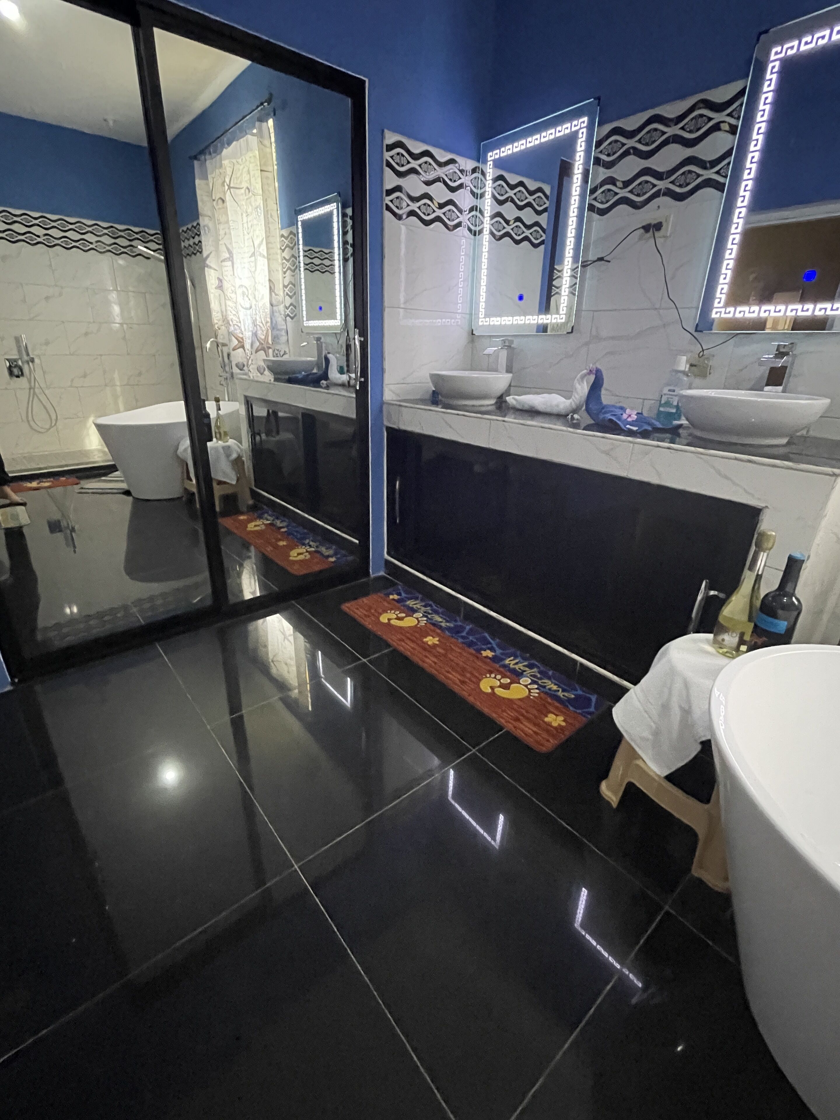 A modern bathroom with a large mirror, white sink, and a bathtub.