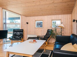 Una habitación con paredes de madera, una mesa blanca, un sofá de cuero negro y dos sillas de cuero.