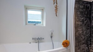 Ein modernes Badezimmer mit freistehender Badewanne, einem Fenster und einer Duschbrause.