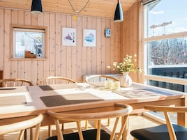 Una habitación con paneles de madera, una mesa de comedor, sillas, obras de arte en las paredes y una ventana con vistas a árboles y peces.