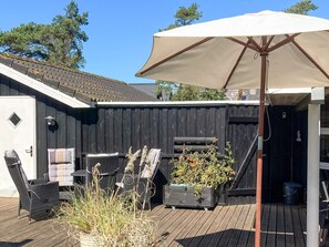 A wooden deck with outdoor furniture, a large umbrella, and a potted plant. - 4 Star Holiday Home in Ebeltoft (Ebeltoft)
