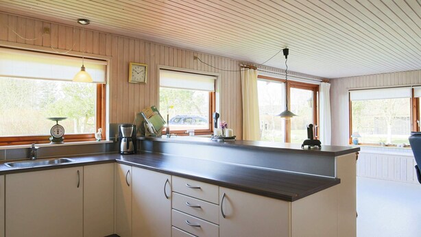 Eine Küche mit Holzboden, Spüle, Schränken und einem Fenster mit Blick nach draußen.