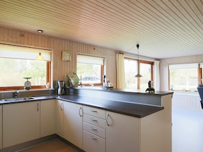 A kitchen with a wooden ceiling, a sink, cabinets, and a window with a view of the outside. - 6 Person Holiday Home in Dannemare (Dannemare)