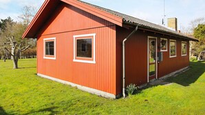 Ein rotes Holzgebäude mit Satteldach, einer Tür und zwei Fenstern.