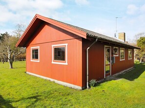 A red wooden building with a pitched roof, a door, and two windows. - 6 Person Holiday Home in Dannemare (Dannemare)