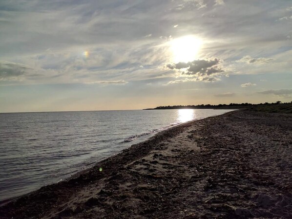 En strand med bred sandstrand og roligt vand.