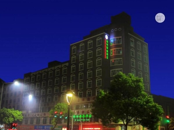A multi-story hotel with a prominent green sign on the facade, a visible moon in the sky, and street lamps in the foreground. - Greentree Inn Zhejiang Ningbo East Tianyi Plaza Baizhuang Road Express Hotel (Ningbo)
