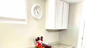 A kitchen with white cabinets, a marble countertop, and a clock on the wall. - The Checkered Daisy Cottage: Colorful and Fun (Price)