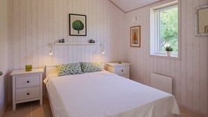 A bedroom with a bed, two bedside tables, a window, and a wall-mounted shelf with decorative items. - 6 Person Holiday Home in Hojby-by Traum (Hojby)