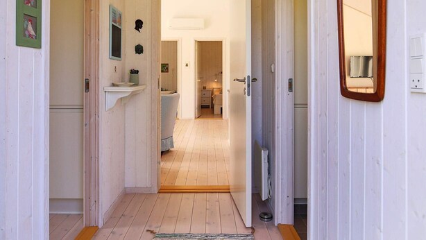 A narrow hallway with wooden floors and white walls, leading to a bedroom with a bed and a nightstand. - 6 Person Holiday Home in Hojby-by Traum (Hojby)