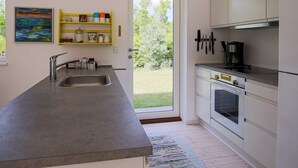 A modern kitchen with a large island, stainless steel appliances, and a view of the garden through the door. - 6 Person Holiday Home in Hojby-by Traum (Hojby)