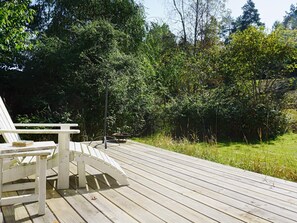 A wooden deck with a white Adirondack chair and a fire pit. - 7 Person Holiday Home in Djurhamn (Djurhamn)