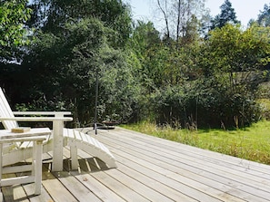 A wooden deck with a white Adirondack chair and a fire pit. - 7 Person Holiday Home in Djurhamn (Djurhamn)