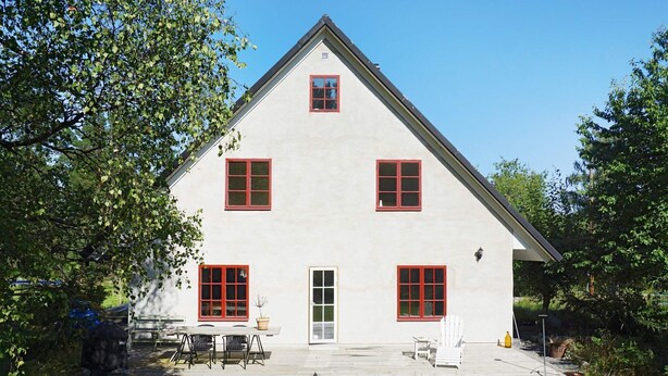 En tvåvåningsbyggnad med en symmetrisk fasad, en central entré och en täckt uteplats med utemöbler.