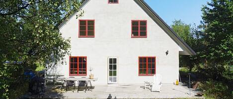 A two-story building with a symmetrical facade, a central entrance, and a covered patio area with outdoor furniture.