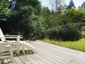 A wooden deck with a white chair and a fire pit. - 7 Person Holiday Home in Djurhamn (Djurhamn)