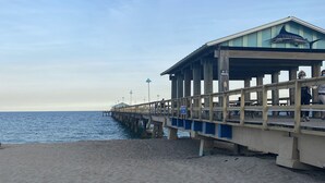 A beach with a wooden pier extending into the ocean.