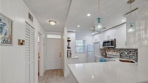 A modern kitchen with white cabinetry, a large island, and pendant lighting.