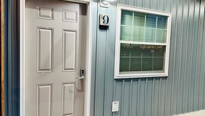 A house with a white door, a window with a number 9 sign, and a light fixture above the door. - Knotty Squirrel Unit 9 Standard King Suite (Mountain View)