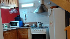 A kitchen with wooden cabinets, a microwave, a stove, and a refrigerator.