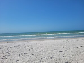 Ein Strand mit blauem Himmel und ruhigem Meer.