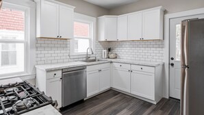 A modern kitchen with white cabinets, a stainless steel refrigerator, and a dishwasher.