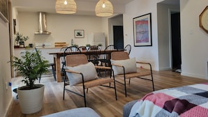 A modern living room with a dining area, featuring wicker chairs, a large potted plant, and a cozy sofa. - Cozy Lakeside Living (Verona)