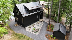 A modern black house with a sloped roof, a front porch, and a small shed. - Cozy Lakeside Living (Verona)