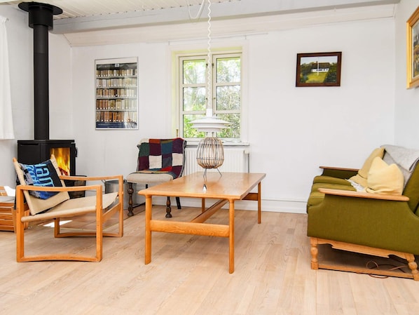 A cozy living room with a fireplace, a wooden table, and a green sofa.