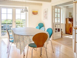 Un comedor con una mesa redonda, sillas y lámparas colgantes.