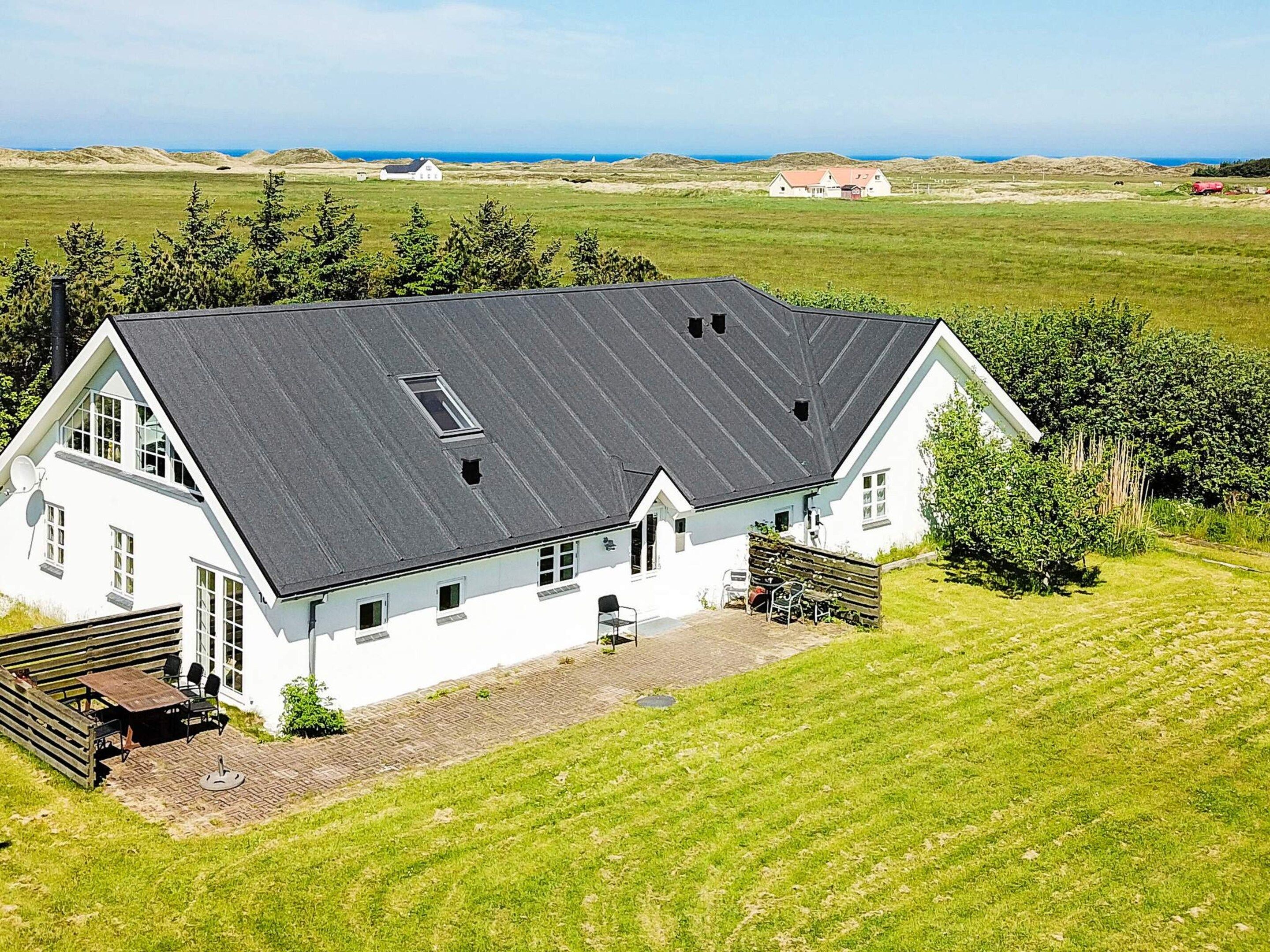 A white building with a sloped roof, a paved driveway, and a grassy lawn.