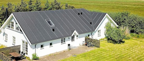 A white building with a sloped roof, a paved driveway, and a grassy lawn.