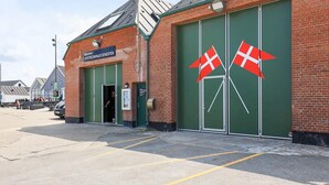 A brick building with green double doors and two Danish flags.